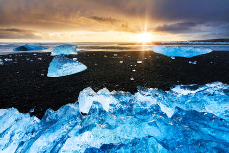 Beautiful beached chunks of ice at the beach at Jokulsarlon, Iceland, at sunset in winterの写真素材