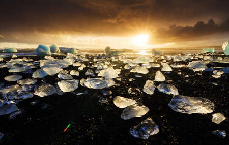 Beautiful beached chunks of ice at the beach at Jokulsarlon, Iceland, at sunset in winterの写真素材
