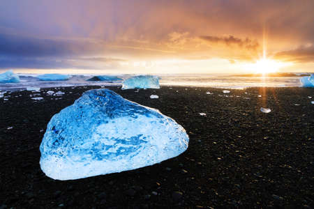 Beautiful beached chunks of ice at the beach at Jokulsarlon, Iceland, at sunset in winterの写真素材