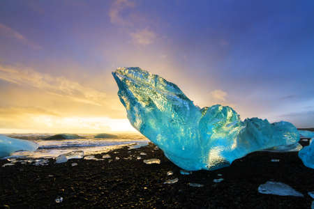 Very large and beautiful chunk of ice at the beach at Jokulsarlon, Iceland, at sunset in winterの写真素材