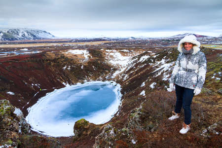 Beautiful woman on the top of the Kerid crater in Iceland in winterの写真素材