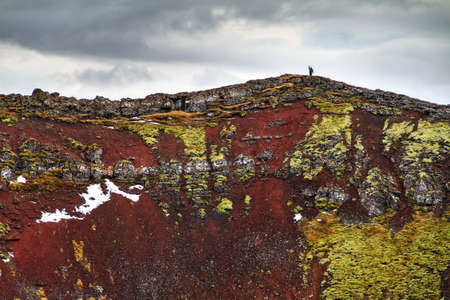 Tourist hiking on top of the volcanic Kerid crater with the lake below, in Iceland in winterの写真素材