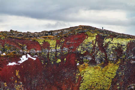 Tourist hiking on top of the volcanic Kerid crater with the lake below, in Iceland in winterの写真素材