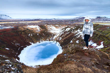 Beautiful woman on the top of the Kerid crater in Iceland in winterの写真素材