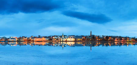 Beautiful panorama of the skyline cityscape of Reykjavik, reflected in lake Tjornin at the blue hour in winterの写真素材