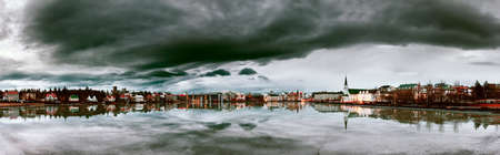 Beautiful panorama of the skyline cityscape of Reykjavik, reflected in lake Tjornin at the blue hour in winterの写真素材