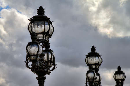 Lanterns on the Pont Alexandre III in Paris against a cloudy skyの写真素材