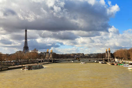 Tourist boat at the Seine in Paris with the Eiffel tower in the background on a cloudy winter dayの写真素材