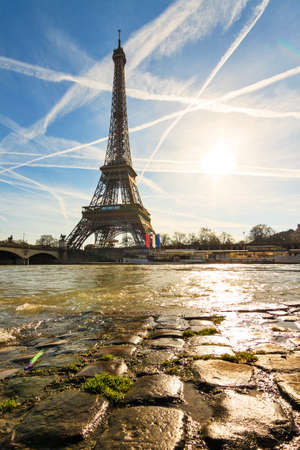 Beautiful backlit Eiffel tower at the Seine river with a dramatic sky in winterの写真素材