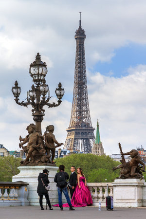 Asian couple does a wedding photo shoot at the pont Alexandre III with the Eiffel tower in the...