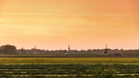 Skyline of Abcoude, the Netherlands, at sunset in spring, view over the rural pastures from Baambrugge with a windmill and churchesの写真素材
