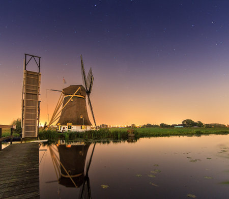 Beautiful traditional historic windmill near Baambrugge and Abcoude in the Netherlands at night with a nice reflection and lots of stars in the skyの写真素材