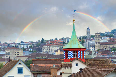 Beautiful cityscape panorama with a green tower in Zurich, Switzerland, with a beautiful rainbow in summerの写真素材
