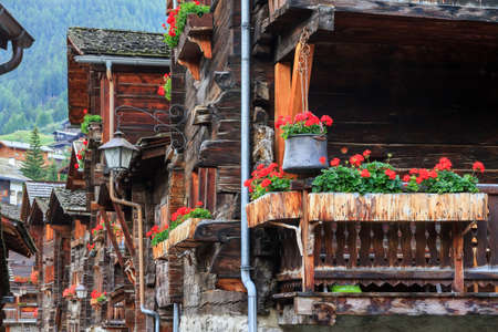 Beautiful traditional wooden houses in the streets of the alpine village Grimentz, Switzerland, in the canton Valais, municipality Anniviers, with geranium flowers on the balconiesのeditorial素材