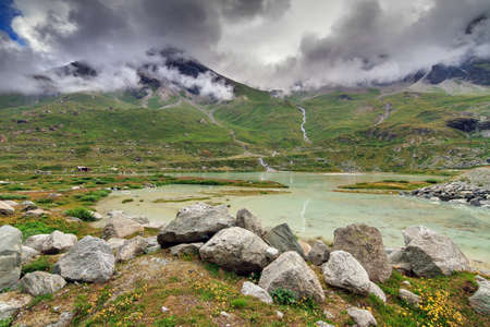 Beautiful alpine landscape at the Moiry glacier with melted ice pools and a ominous sky with clouds in summer in the Swiss pennine alps near Grimentz, Valais, Switzerlandの写真素材