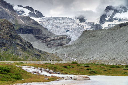 Beautiful landscape at the Moiry glacier with melted ice pools and a ominous sky with clouds in summer in the Swiss pennine alps near Grimentz, Valais, Switzerlandの写真素材