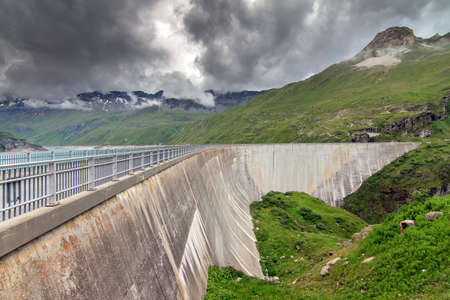Beautiful view of the concrete dam of the reservoir lake Lac de Moiry in the alps near Grimentz, Switzerland, on a cloudy summer dayの写真素材