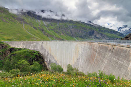 Beautiful view of the concrete dam of the reservoir lake Lac de Moiry in the alps near Grimentz, Switzerland, on a cloudy summer dayの写真素材