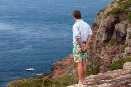 Beautiful young tourist looking at the sea on the edge of the cliffs at Cap FrÃ©hel in Brittany, France, in summerの写真素材