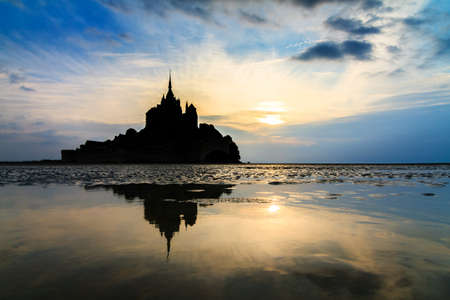 Beautiful view of historic landmark Le Mont Saint-Michel in Normandy, France, a famous UNESCO world heritage site and tourist attraction, at sunset with reflectionのeditorial素材