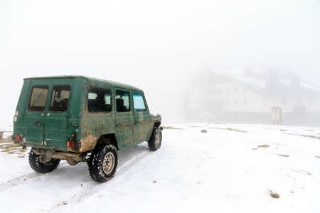 Old 4x4 car in the snow and fog at the hotel in the Rila Nature Park at the Rila lakes im Bulgaria in autumnの写真素材