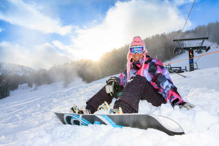 Beautiful young woman ready to snowboard on the snowy ski slopes on a sunny day in the Alps in the Brandnertal, Vorarlberg Austriaの写真素材