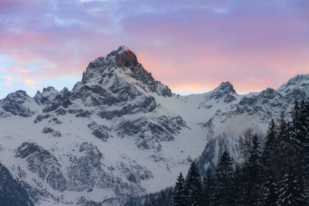 Beautiful evening sunset view of mountain tops with snow and vibrant clouds in the Brandnertal in...
