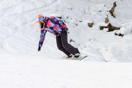 Beautiful young woman snowboarding on the snowy ski slopes on a winter day in the Alps in the Brandnertal, Vorarlberg Austriaの写真素材