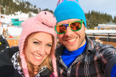 Beautiful selfie portrait of a young couple on wintersport vacation with vibrant colors on a sunny day in the Alps in the Brandnertal, Vorarlberg Austriaの写真素材
