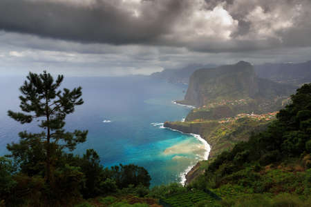 Beautiful dramatic view of the island Madeira with a vibrant green ocean and ominous clouds seen during a levada hikeの写真素材