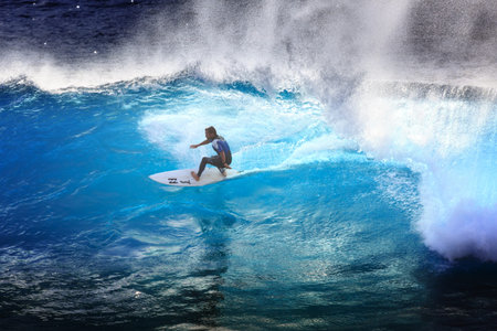 Surfer riding the big blue surf waves on the island Madeira, Portugal, a popular surfing tourist...