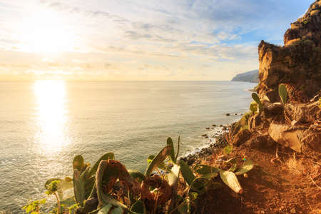 Beautiful backlit landscape view of the coastline cliffs at Tuneis antigos near Ponta do Sol on the east coast of Madeira island, at sunset with the atlantic ocean in summerの写真素材