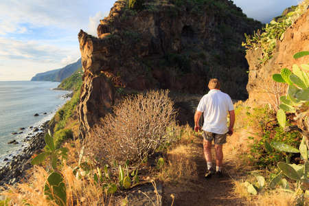 Senior tourist hiking at Tuneis antigos near Ponta do Sol on the east coast of Madeira island, at sunset with the atlantic ocean in summerの写真素材