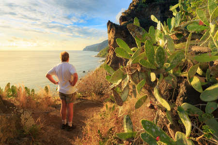 Senior tourist hiking at Tuneis antigos near Ponta do Sol on the east coast of Madeira island, at sunset with the atlantic ocean in summerの写真素材
