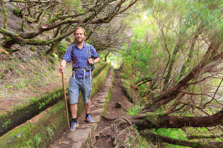 Beautiful landscape view of a young handsome tourist on the hiking trail in nature on the green island Madeiraの写真素材