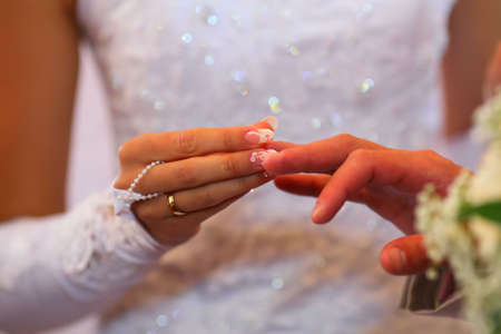 groom`s and bride`s hands with golden wedding ringsの写真素材