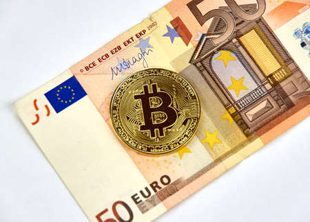 MONTREAL, CANADA - MARCH 10, 2018: Bitcoin cryptocurrency gold coin and logo on Fifty Euro bank note.のeditorial素材
