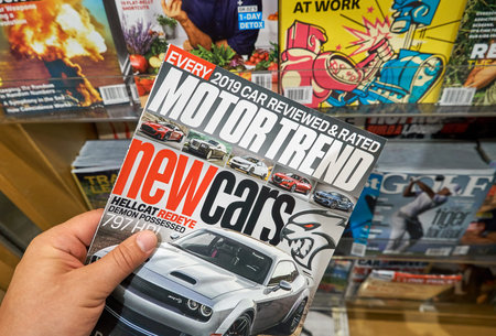 MIAMI, USA - AUGUST 22, 2018: magazine in a hand over a stack of magazines. Motor Trend is a popular...