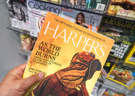 MIAMI, USA - AUGUST 22, 2018: Harper's magazine in a hand over a stack of magazines. Harper's Magazine is a popular monthly magazine of literature, culture, finance and artsのeditorial素材