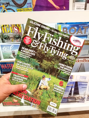 TORONTO, CANADA - DECEMBER 9, 2018: Fly Fishing and Fly Tying magazine in a hand over a stack of...