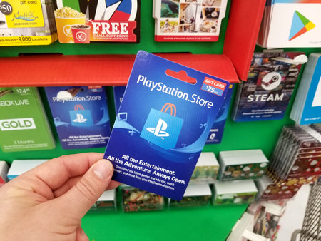 PLATTSBURGH, USA - JANUARY 21, 2019 : Play Station gift card in a hand over a shelves with different...