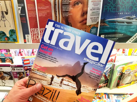 AMSTERDAM, NETHERLANDS: - OCTOBER 8, 2018: The Sunday Times Travel magazine in a hand over a stack of magazines. The Sunday Times Travel Magazine is a monthly British travel magazine.のeditorial素材