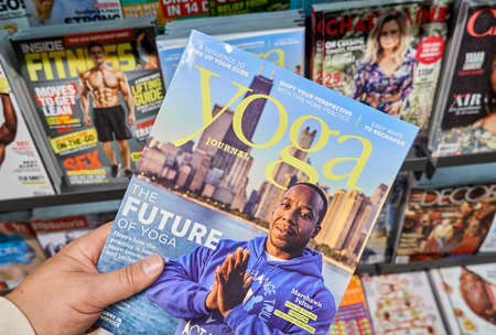 MONTREAL, CANADA - OCTOBER 9, 2018: Yoga Journal with Marshawn Feltus in a hand over a stack of magazines. Yoga Journal is an American media company that publishes a magazine, makes dvds etc.のeditorial素材