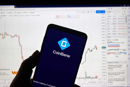 MONTREAL, CANADA - APRIL 26, 2019: Coinbene cryptocurrency exchange logo and application on Android Samsung Galaxy s9 Plus screen in a hand over a laptop display with bitcoin chart on it.のeditorial素材