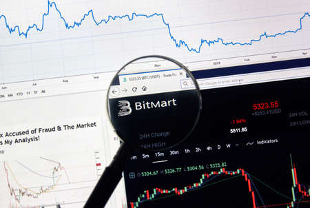 MONTREAL, CANADA - APRIL 26, 2019: Bitmart.com cryptocurrency digital assets exchange logo and home page on a laptop screen under magnifying glass.のeditorial素材