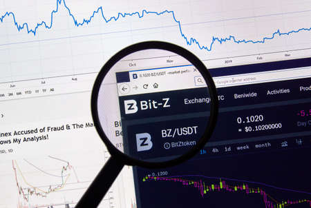 MONTREAL, CANADA - APRIL 26, 2019: Bit-z cryptocurrency digital assets exchange logo and home page on a laptop screen under magnifying glass.のeditorial素材
