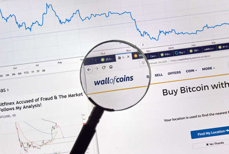 MONTREAL, CANADA - APRIL 26, 2019: Wallofcoins.com cryptocurrency digital assets exchange logo and home page on a laptop screen under magnifying glass.のeditorial素材