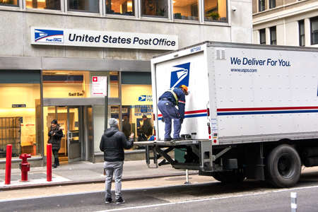 NEW YORK, USA - DECEMBER 14, 2018: USPS postman on a mail delivery truck in New York. USPS is an independent agenc of US federal government responsible for providing postal service in the US.のeditorial素材
