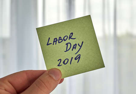 a hand holding Labor Day writing written on a sticky noteの写真素材