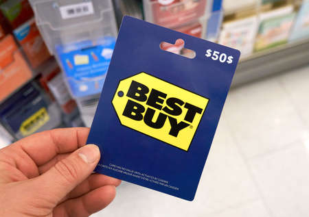 Montreal, Canada - March 24, 2020: Best Buy gift card in a hand at store over gift cards. Best Buy is an American multinational consumer electronics retailer headquartered in Richfieldのeditorial素材